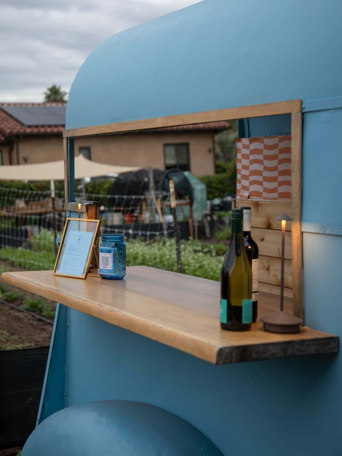The Revelrita bar cart window with a live edge bar top, wine bottles and a framed cocktail menu