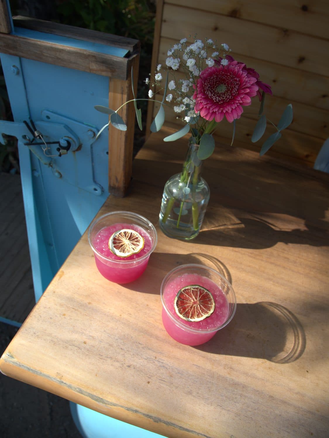 Two pink margaritas with dried lime wheels on the live edge bar top