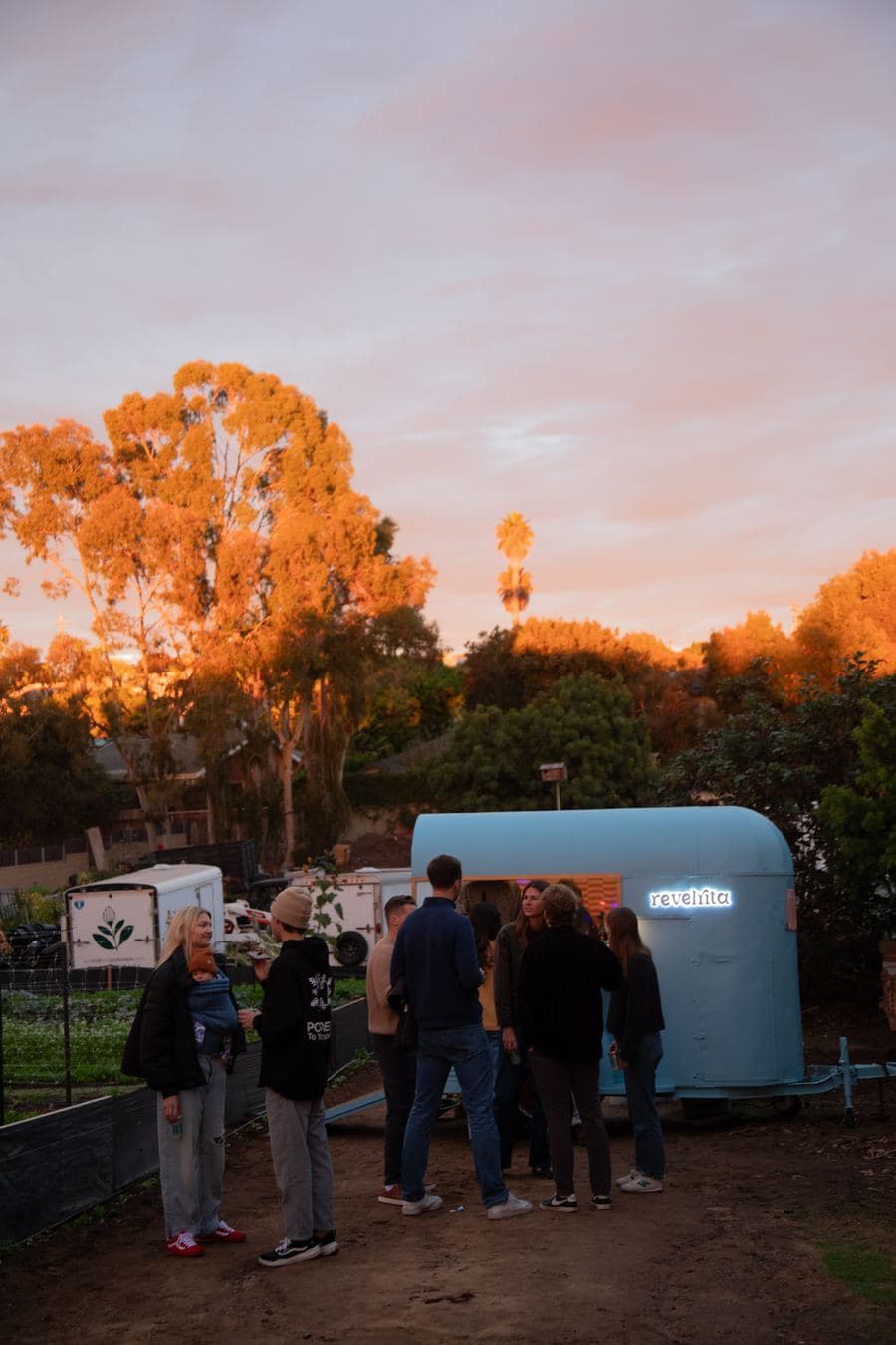 Guests around the cart under a pink sunset sky